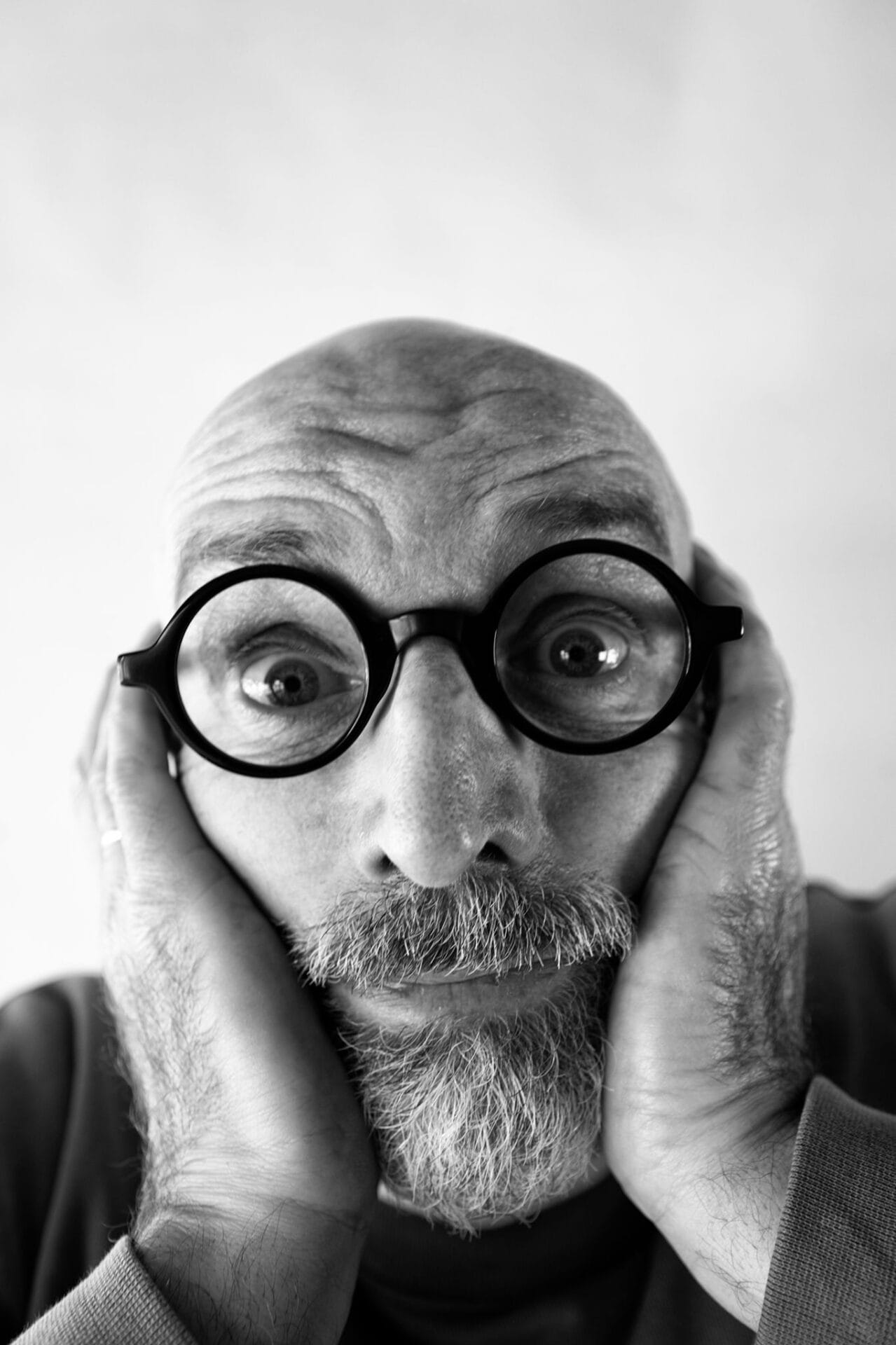 Schwarz-Weiß Portrait eines älteren Mannes mit gerunzelter Stirn, Brille und Bart.