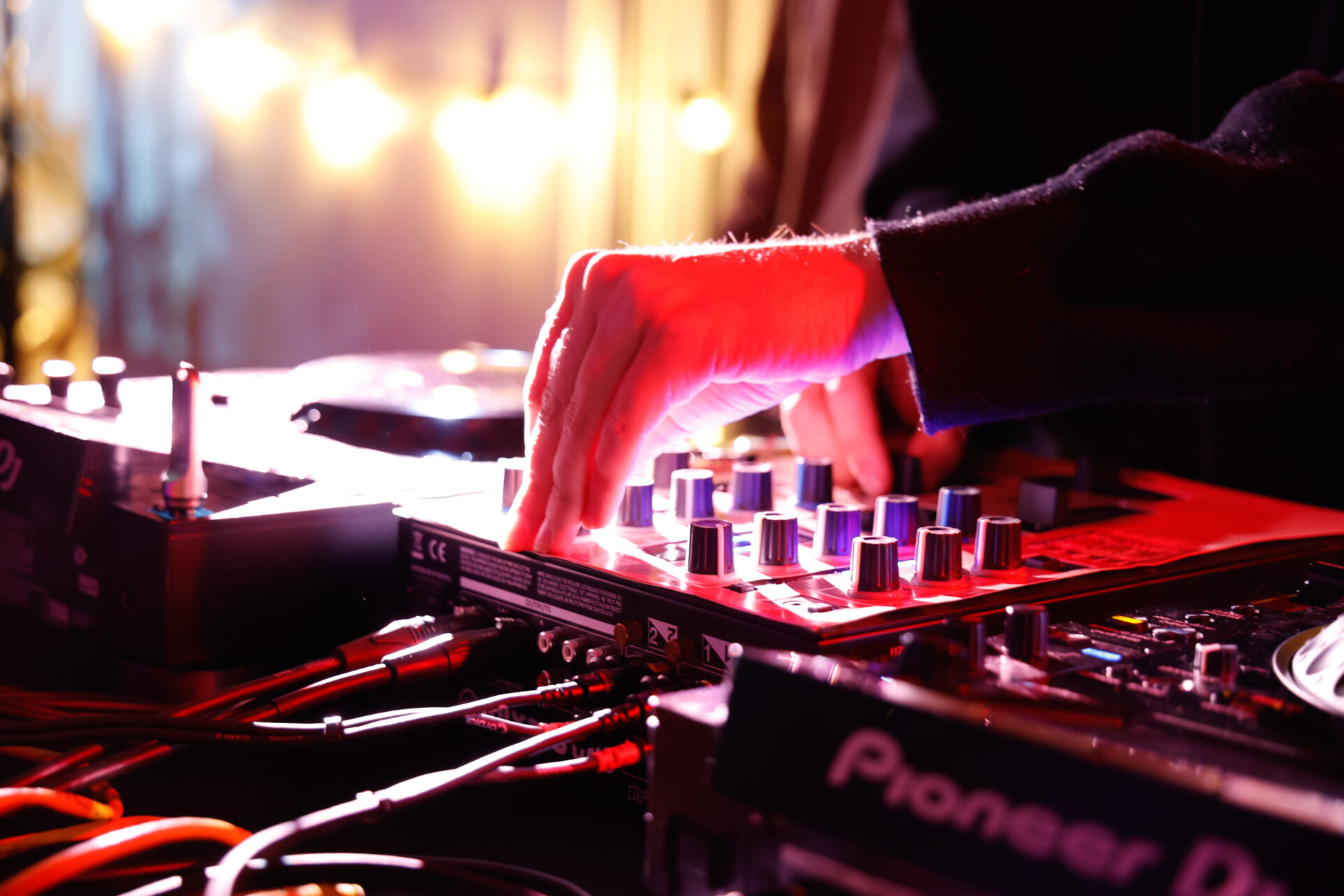 Eine Hand dreht an einem Regler eines DJ-Pults.