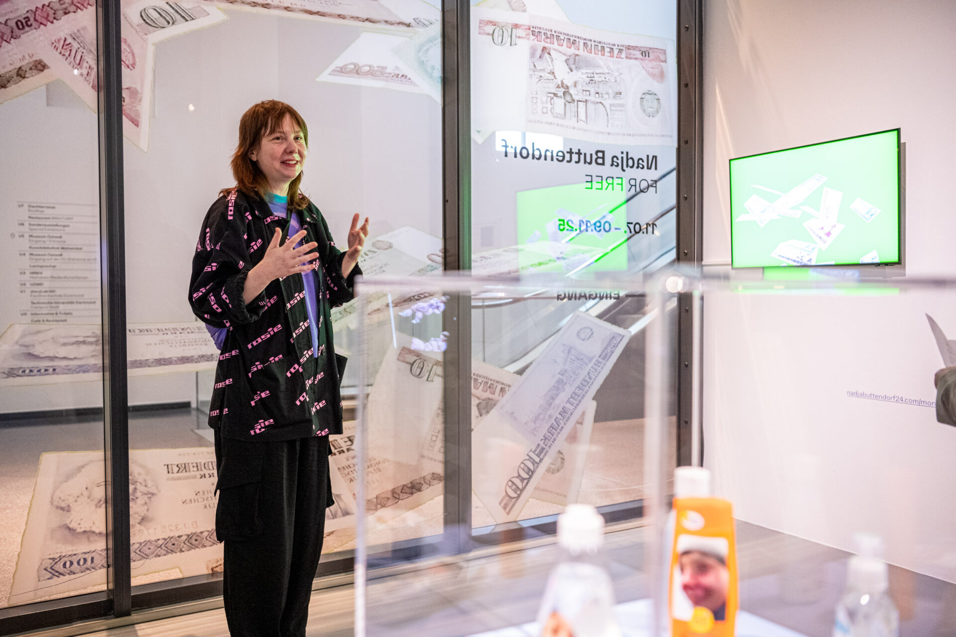 Künstlerin Nadja Buttendorf in ihrer Ausstellung „FOR FREE“ im MO_Schaufenster. Die Schau thematisiert den freien Zugang zu digitaler Kunst und lädt Besucherinnen ein, Werke herunterzuladen, mitzunehmen und weiterzuverwenden.