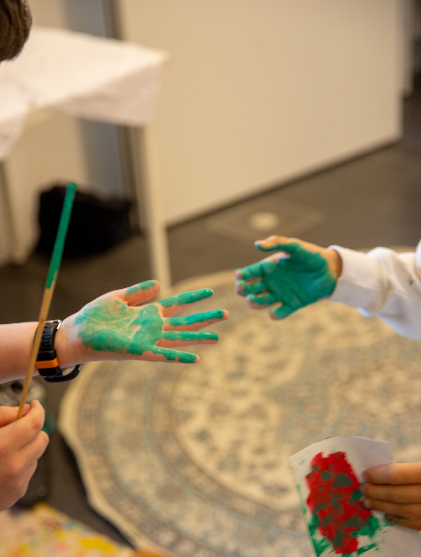 Das Bild zeigt zwei Kinderhände die mit grüner Farbe bemalt sind.