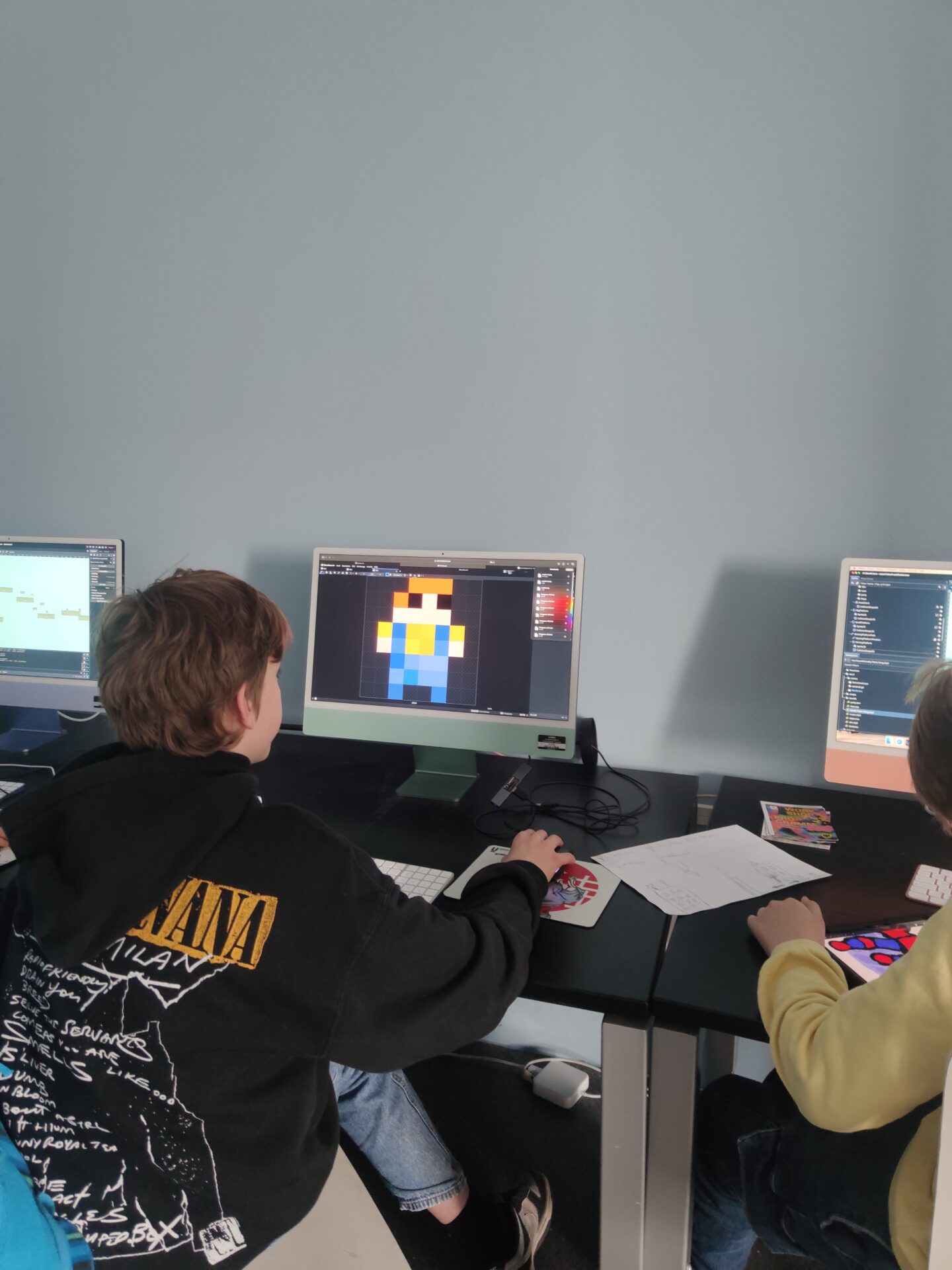 Das Bild zeigt einen Jungen an einem Computer, wie er mit Pixeln eine Figur designt.