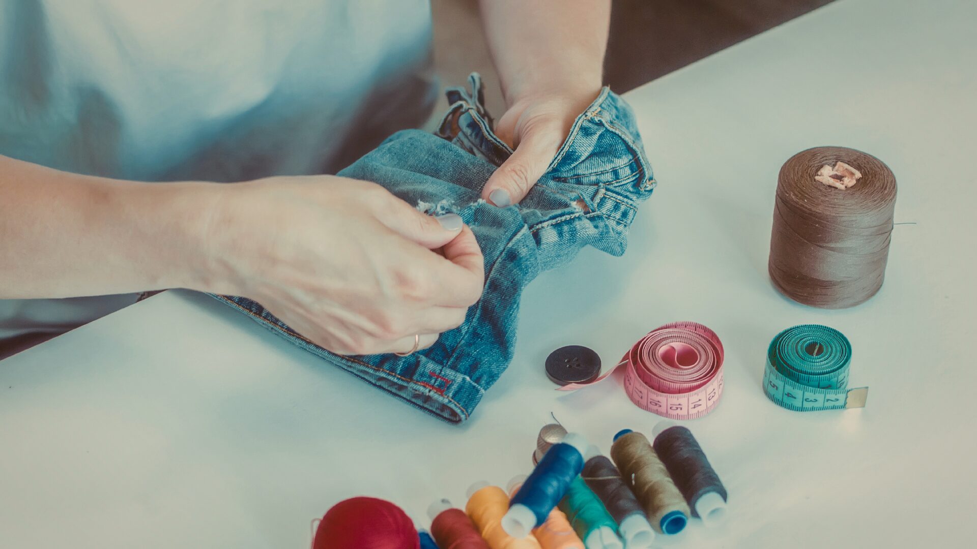 Eine Person näht sorgfältig eine Jeans.