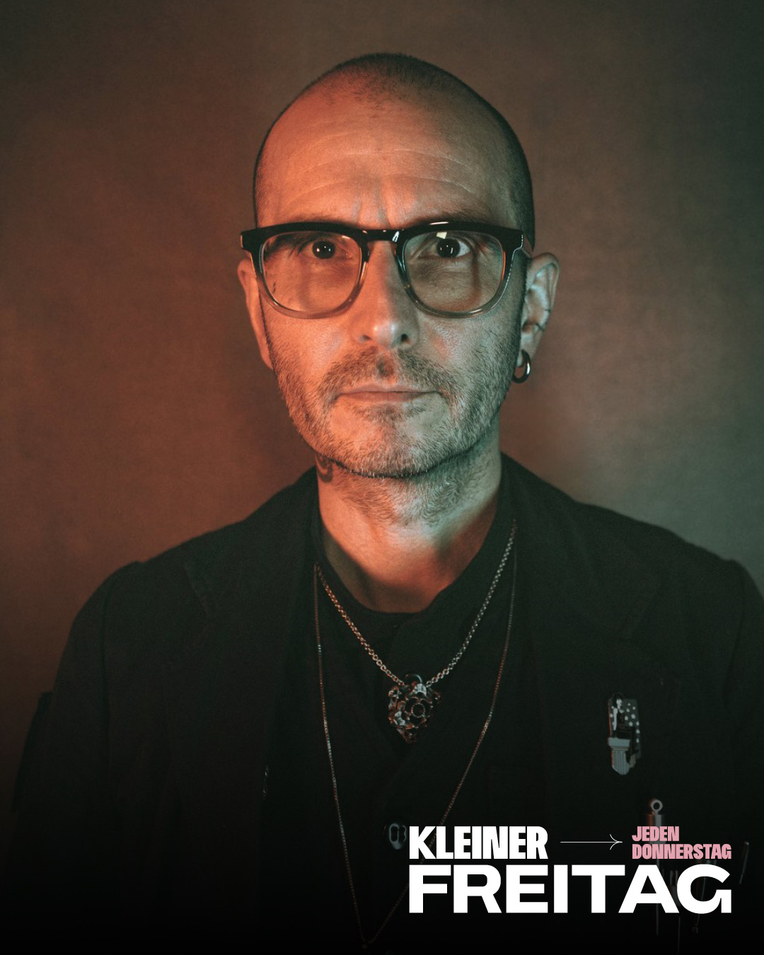 Porträt einer Person mit Brille und Ohrring vor braunem Hintergrund
