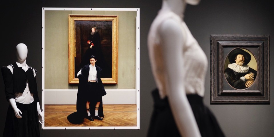 Ein Blick in die Ausstellung mit Schaufensterpuppen, die aktuelle Mode tragen, sowie einer Fotoarbeit und einem Gemälde im Hintergrund.