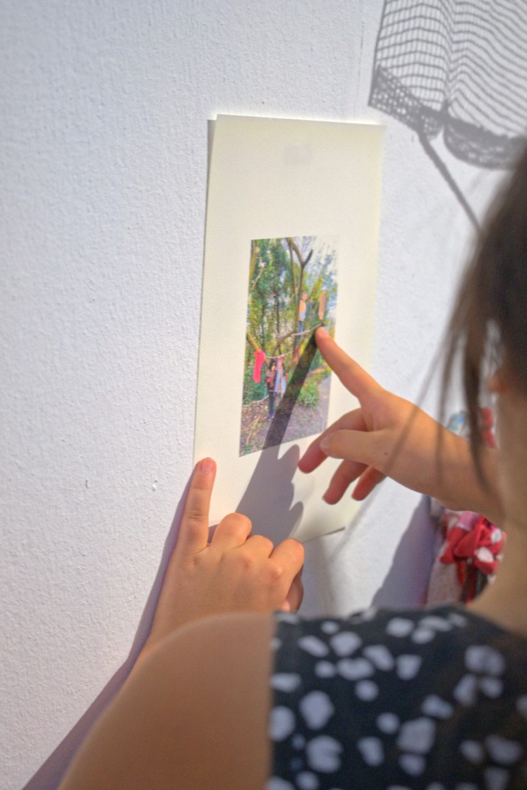 Zwei Personen zeigen auf ein kleines Bild das an der Wand hängt.
