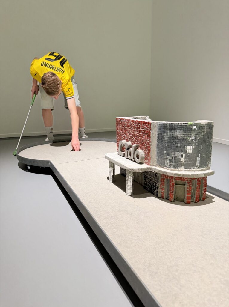 Die Freunde des MO spielen in der Ausstellung "Zurück zum Beton: Ina Webers Trümmerbahnen-Minigolf" im Museum Ostwall