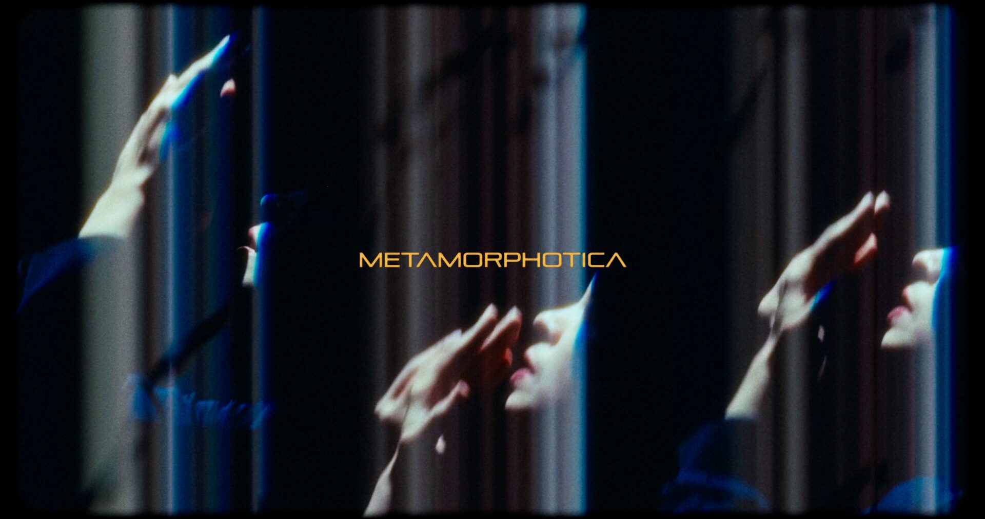 Standbild aus Trailer des Projekts ‘Metamorphotica’ (Fachhochschule Dortmund): verzerrte Hände und Gesichter in Blau- und Violetttönen mit dem Schriftzug ‘Metamorphotica’ in dunkelgelb