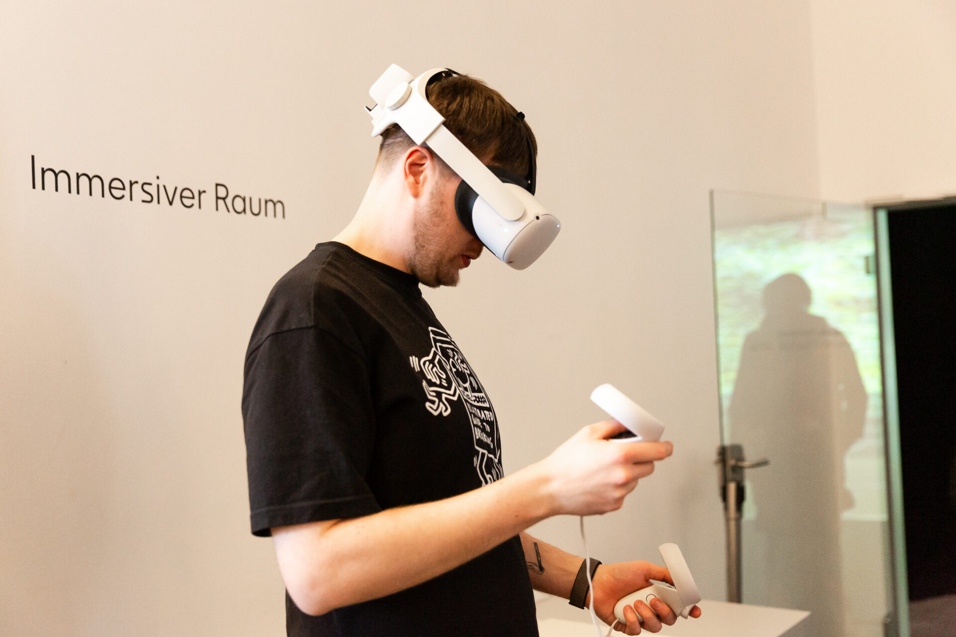 Eine Person trägt eine VR Brille und hält Steuerungsgriffe in den Händen.