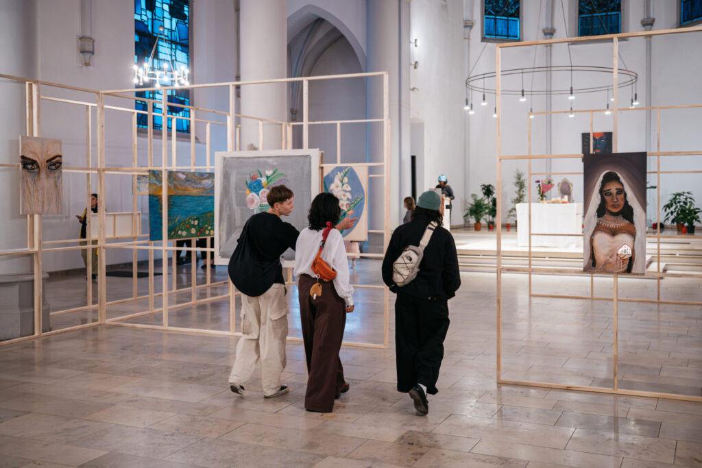 Drei Personen betrachten Kunstwerke in einer Kirche