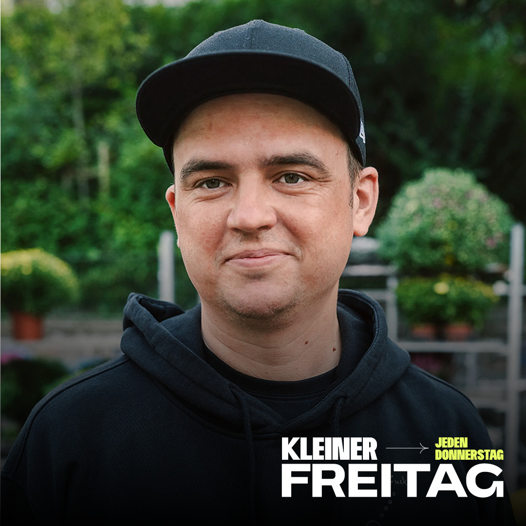 Porträt eines Mannes mit schwarzer Kappe und schwarzem Hoodie vor unscharfem Hintergrund mit Pflanzen