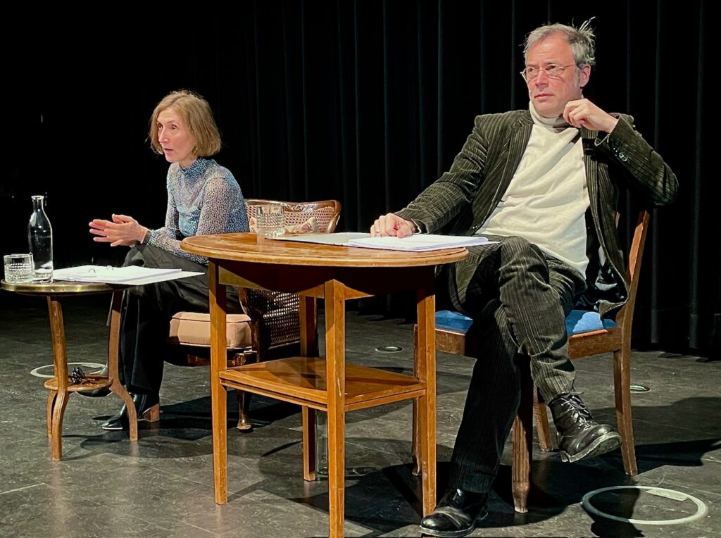 Foto während der Vorführung des Theaterstücks "Love letters". Zwei protagonist*innen sitzen am Tisch